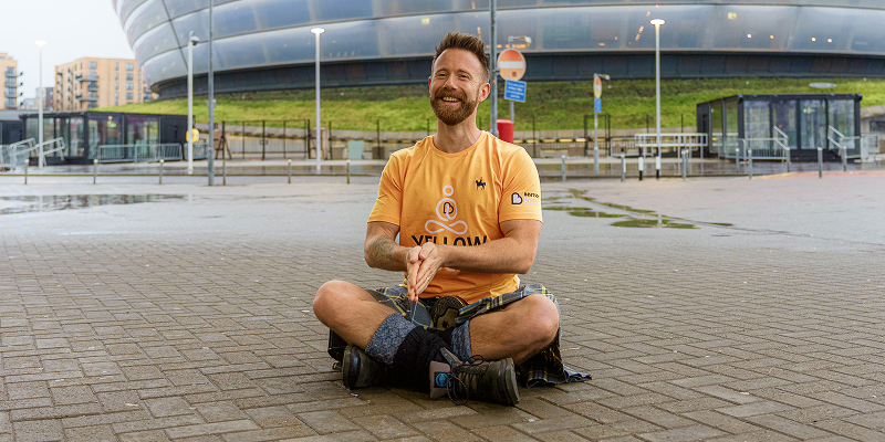 The Kilted Yogi sits cross legged outside the OVO Hydro