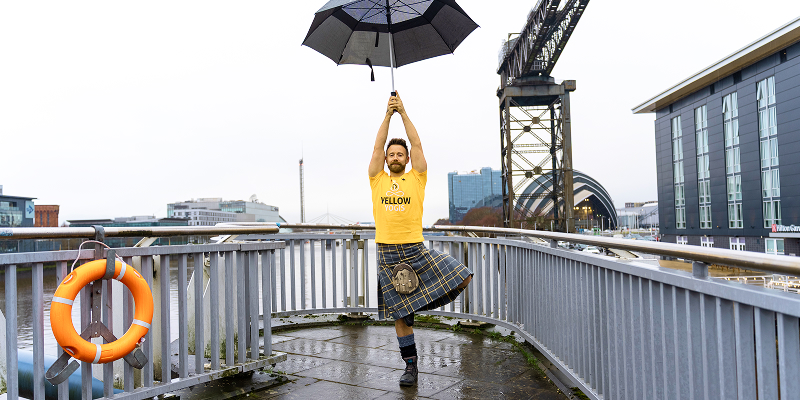 The Kilted Yogi poses with an umbrella in front of the Finnieston Crane
