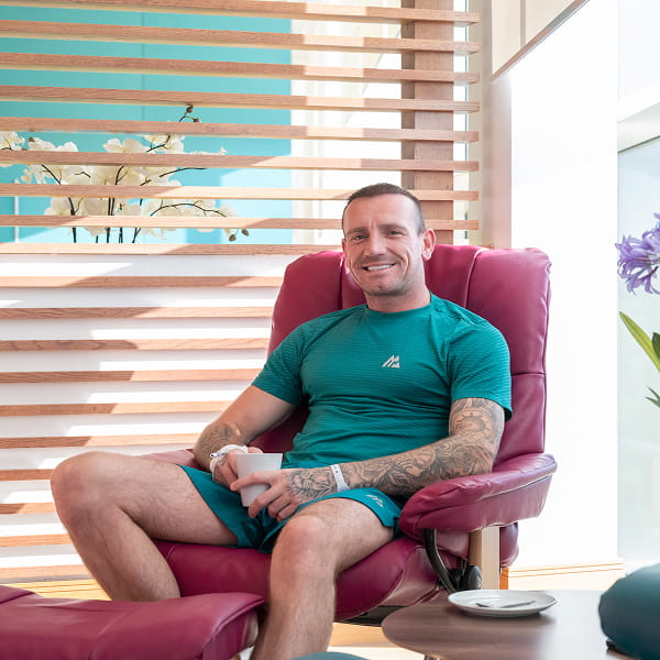 Man sitting on chair and smiles towards camera inside the Beatson Wellbeing Centre